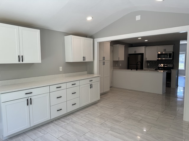 kitchen featuring decorative backsplash, vaulted ceiling, stainless steel appliances, and white cabinets