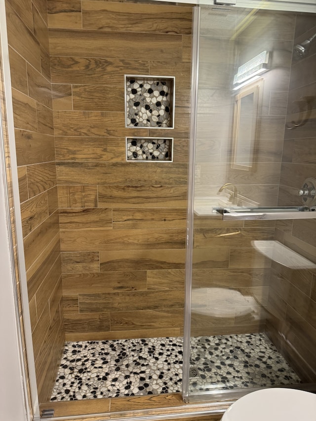 bathroom featuring toilet and a shower with door