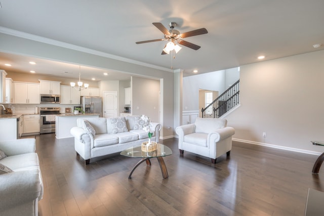 living room with ornamental molding, sink, ceiling fan with notable chandelier, and dark wood-type flooring