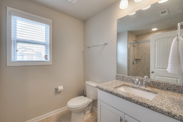 bathroom featuring a tile shower, vanity, tile patterned flooring, and toilet