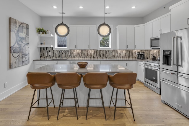 kitchen featuring white cabinets, hanging light fixtures, high end appliances, and a center island