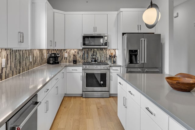 kitchen featuring pendant lighting, white cabinetry, light hardwood / wood-style floors, and high quality appliances