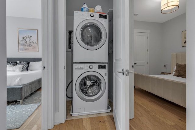 laundry area with light hardwood / wood-style flooring and stacked washing maching and dryer