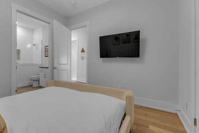 bedroom with connected bathroom and light hardwood / wood-style floors