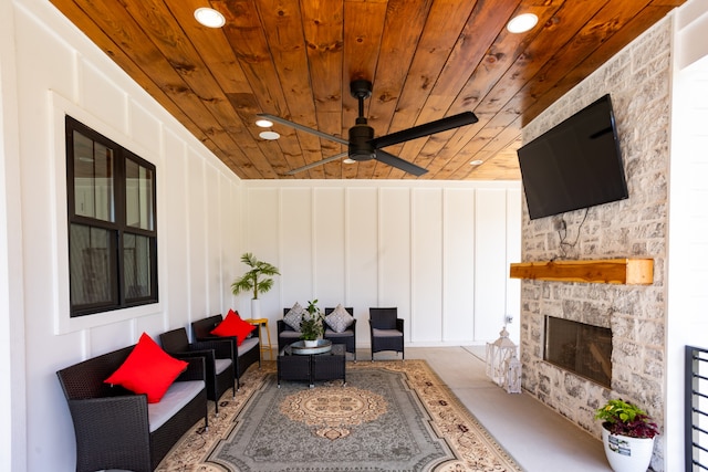 exterior space featuring wood ceiling, a stone fireplace, and ceiling fan