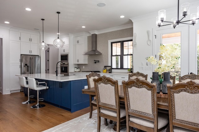 6821 Springwater St, Smyrna, TN 37167 - kitchen featuring light countertops, appliances with stainless steel finishes, wall chimney range hood, white cabinets, and an inviting chandelier