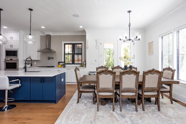 dining space with ornamental molding, a chandelier, light hardwood / wood-style floors, and sink