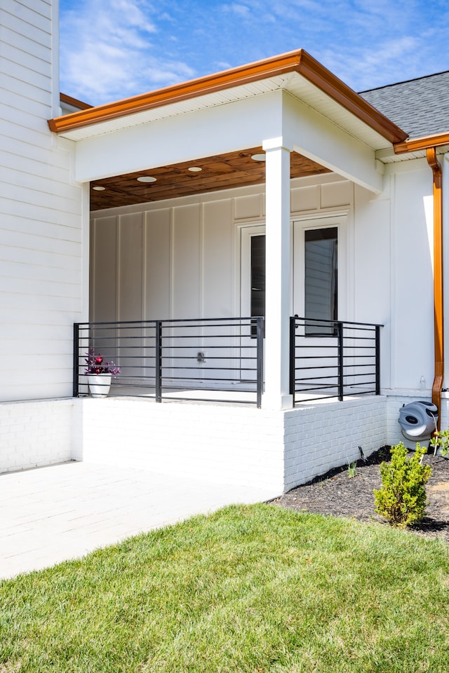 view of exterior entry with a porch and a yard