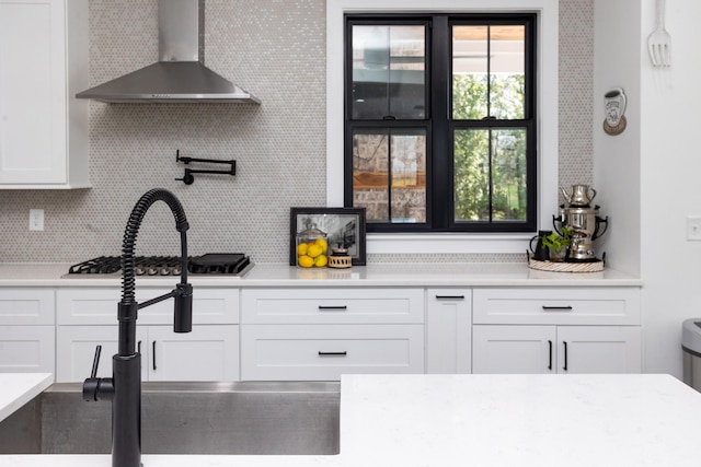 6821 Springwater St, Smyrna, TN 37167 - kitchen with white cabinetry, stainless steel gas cooktop, decorative backsplash, a sink, and wall chimney range hood