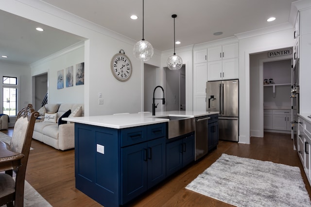 kitchen with an island with sink, sink, white cabinetry, blue cabinetry, and appliances with stainless steel finishes