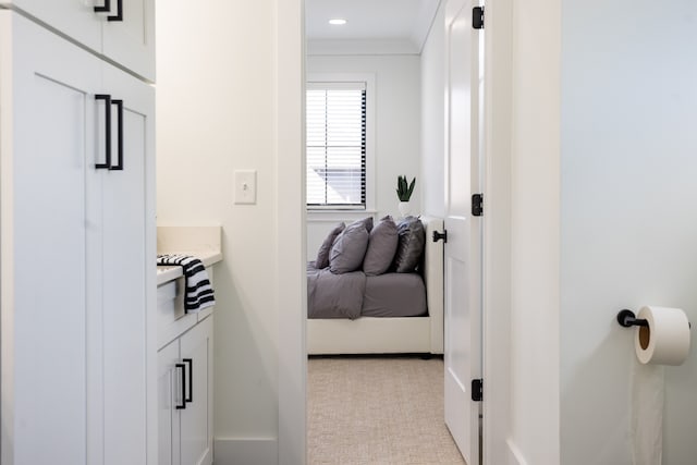 hall with crown molding and light colored carpet