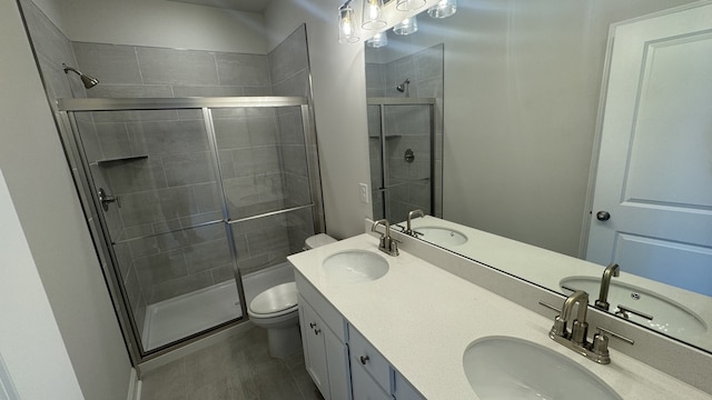 bathroom featuring a shower with door, vanity, and toilet