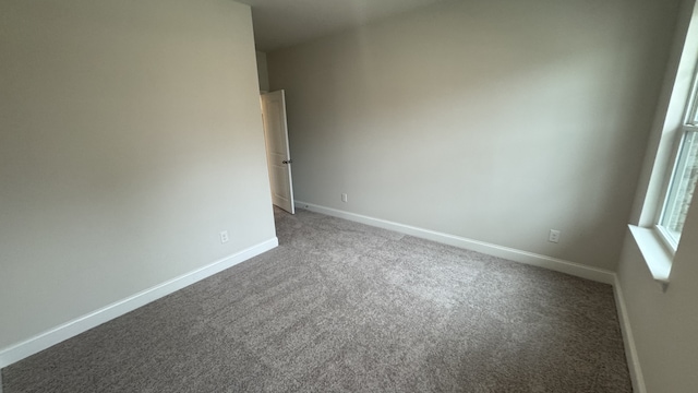 unfurnished room featuring dark colored carpet