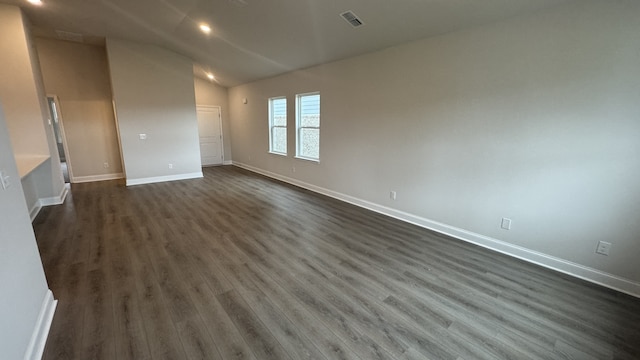 spare room with dark wood-type flooring and vaulted ceiling