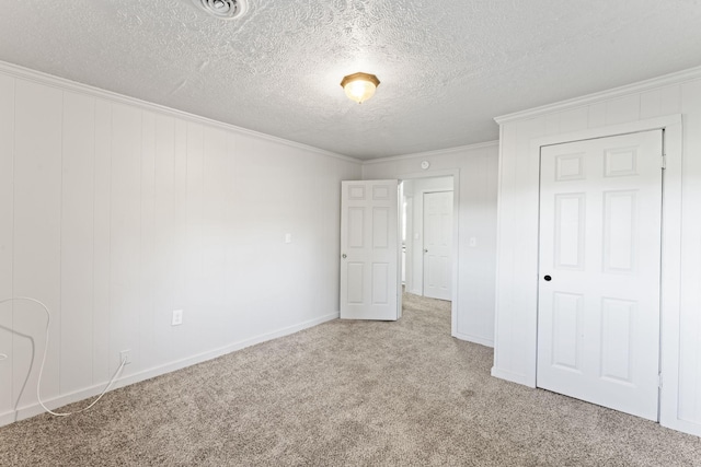 unfurnished bedroom featuring visible vents, a textured ceiling, carpet, crown molding, and baseboards