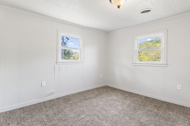 empty room featuring visible vents, baseboards, ornamental molding, carpet flooring, and a textured ceiling