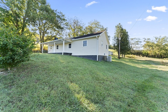 back of property featuring a lawn and central AC