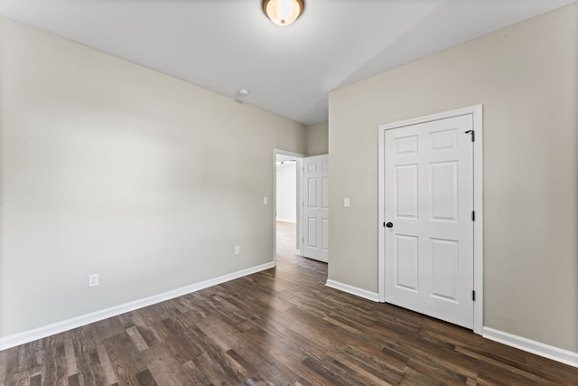 unfurnished bedroom with vaulted ceiling, a closet, and dark hardwood / wood-style flooring