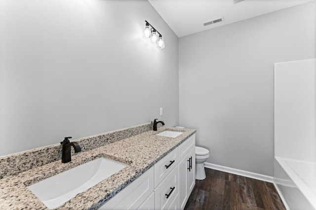 bathroom with a washtub, wood-type flooring, vanity, and toilet