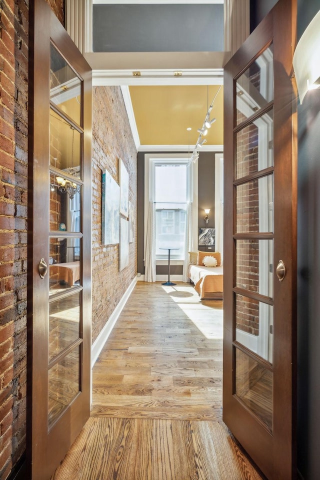 hallway with crown molding, brick wall, and wood finished floors