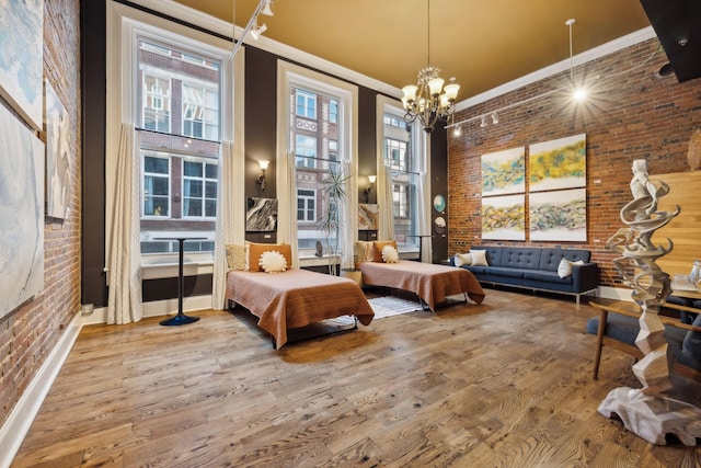 bedroom featuring a towering ceiling, wood finished floors, crown molding, and brick wall