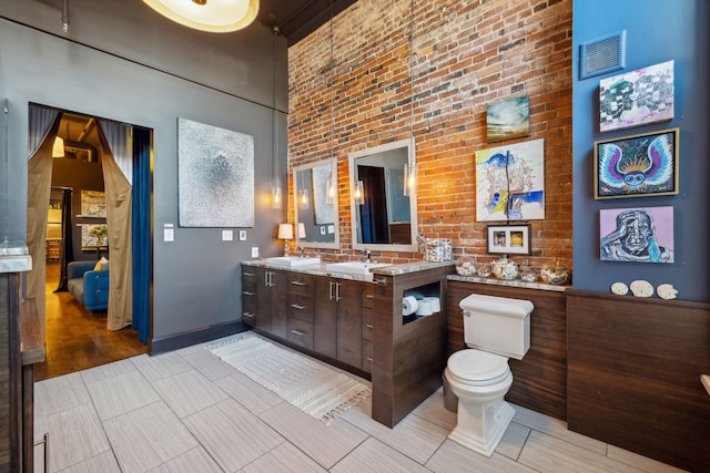 bathroom with toilet, a sink, a towering ceiling, visible vents, and double vanity