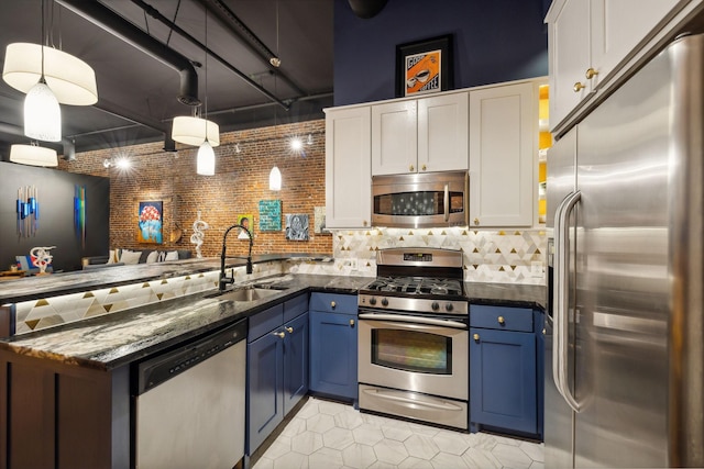 kitchen with a peninsula, blue cabinetry, stainless steel appliances, white cabinetry, and a sink