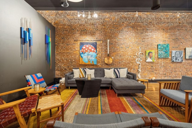 living area featuring wood finished floors and brick wall
