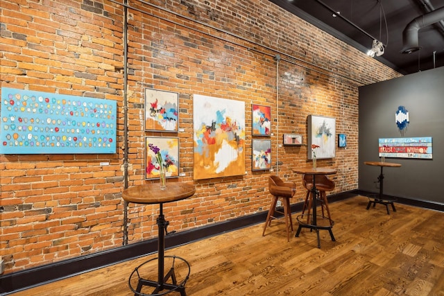 bar featuring baseboards, brick wall, and wood finished floors