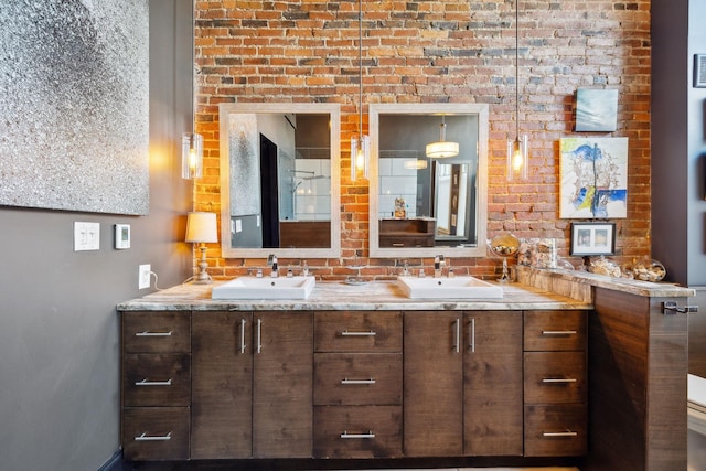 bathroom featuring double vanity, a sink, and brick wall