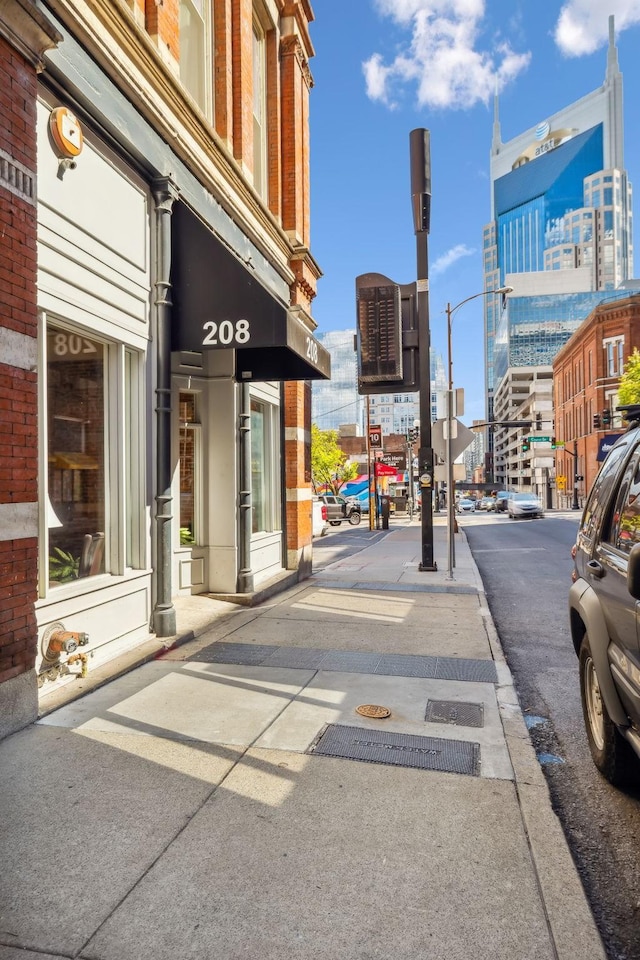 view of road featuring sidewalks, street lights, a view of city, and curbs
