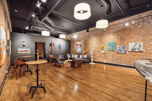 miscellaneous room featuring a high ceiling, wood finished floors, and brick wall