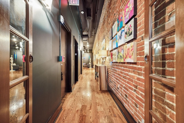 corridor with wood finished floors and brick wall