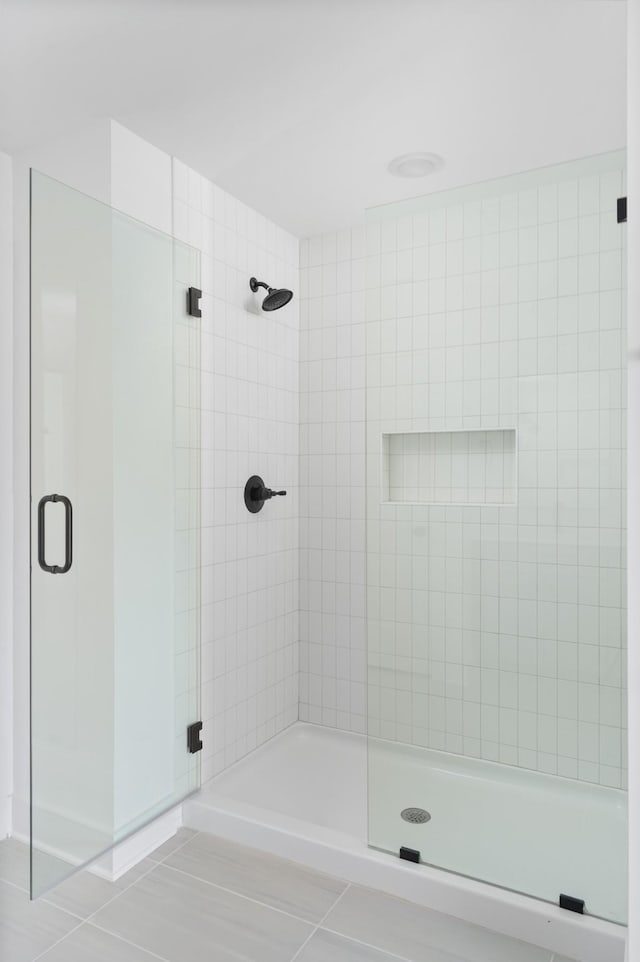 bathroom with a shower with shower door and tile patterned flooring