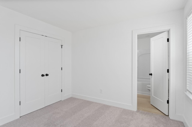 unfurnished bedroom featuring a closet and light carpet