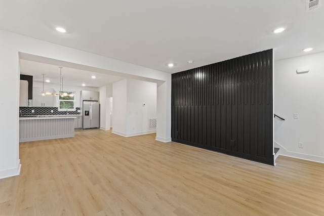 unfurnished living room with light hardwood / wood-style floors and a chandelier