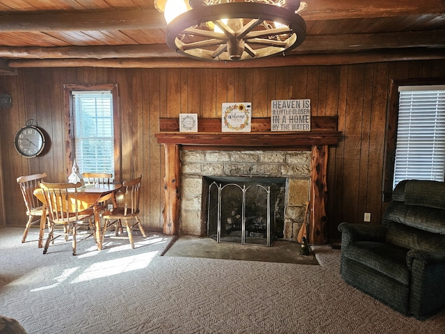 living room with carpet floors, wood walls, a stone fireplace, and wooden ceiling