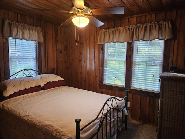 carpeted bedroom with ceiling fan, wooden walls, and wooden ceiling