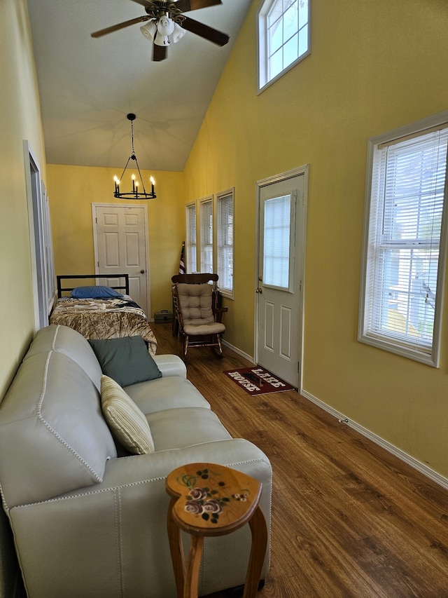 living room with ceiling fan with notable chandelier, high vaulted ceiling, a healthy amount of sunlight, and dark hardwood / wood-style floors