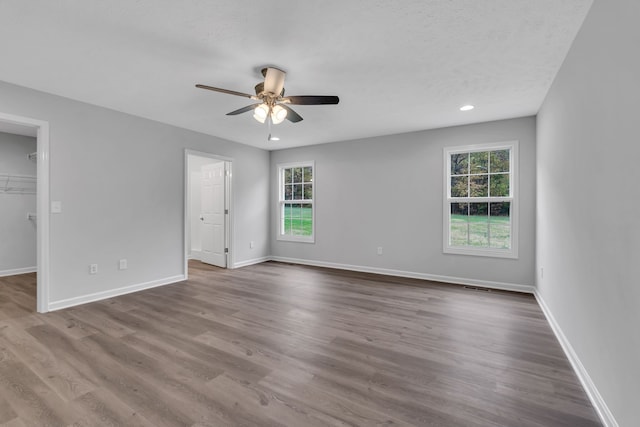 spare room with a textured ceiling, hardwood / wood-style floors, a healthy amount of sunlight, and ceiling fan