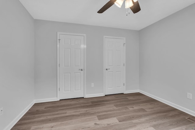 unfurnished bedroom with multiple closets, light hardwood / wood-style flooring, and ceiling fan