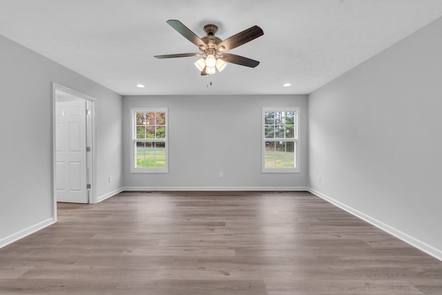 unfurnished room with a wealth of natural light, hardwood / wood-style flooring, and ceiling fan