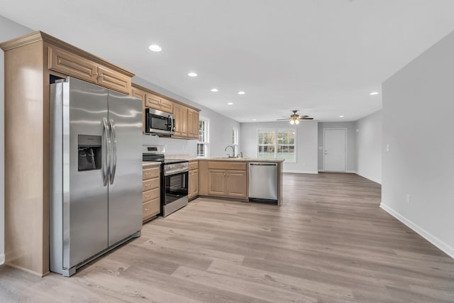 kitchen with stainless steel appliances, kitchen peninsula, sink, ceiling fan, and light hardwood / wood-style flooring