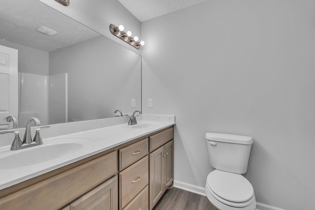 bathroom with hardwood / wood-style floors, vanity, a textured ceiling, and toilet