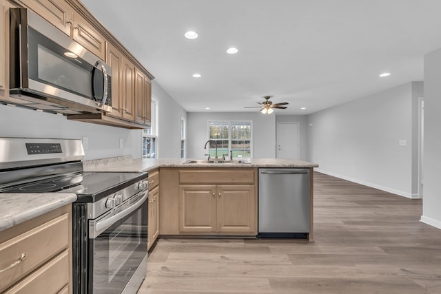 kitchen with stainless steel appliances, sink, light hardwood / wood-style floors, kitchen peninsula, and ceiling fan