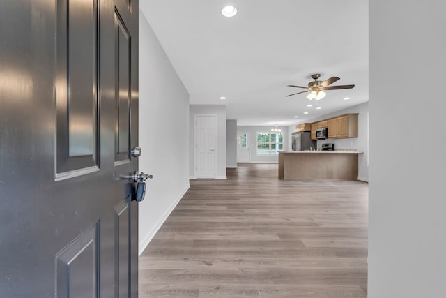 entryway featuring light wood-type flooring and ceiling fan with notable chandelier