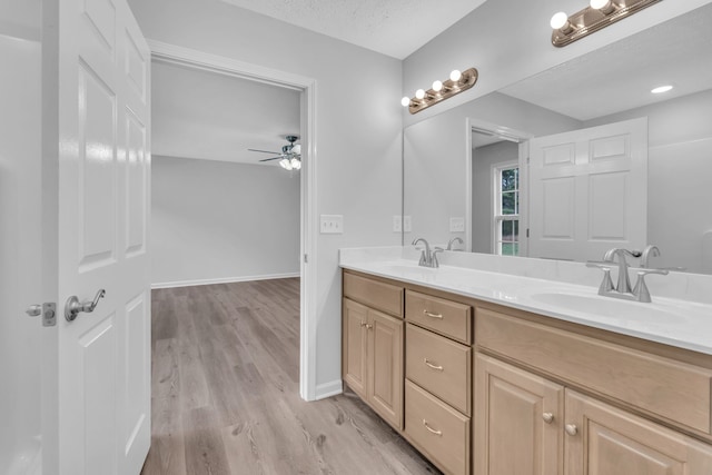 bathroom with vanity, hardwood / wood-style flooring, ceiling fan, and a textured ceiling