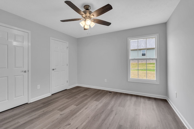 unfurnished bedroom with light wood-type flooring, ceiling fan, and two closets