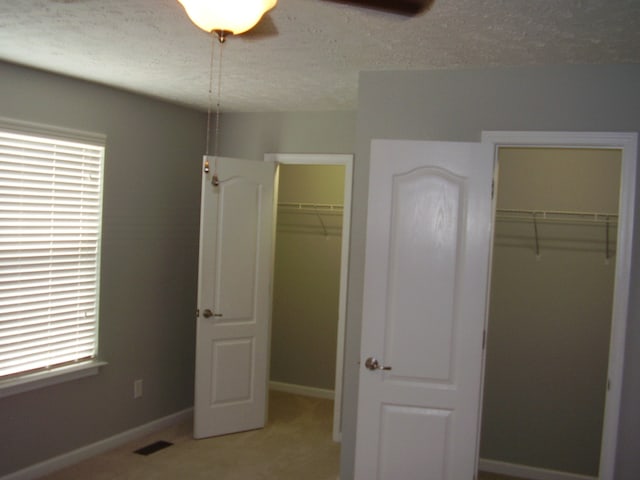 unfurnished bedroom featuring multiple windows, ceiling fan, and a textured ceiling