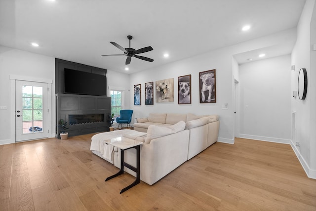 living room featuring a large fireplace, light hardwood / wood-style floors, and ceiling fan